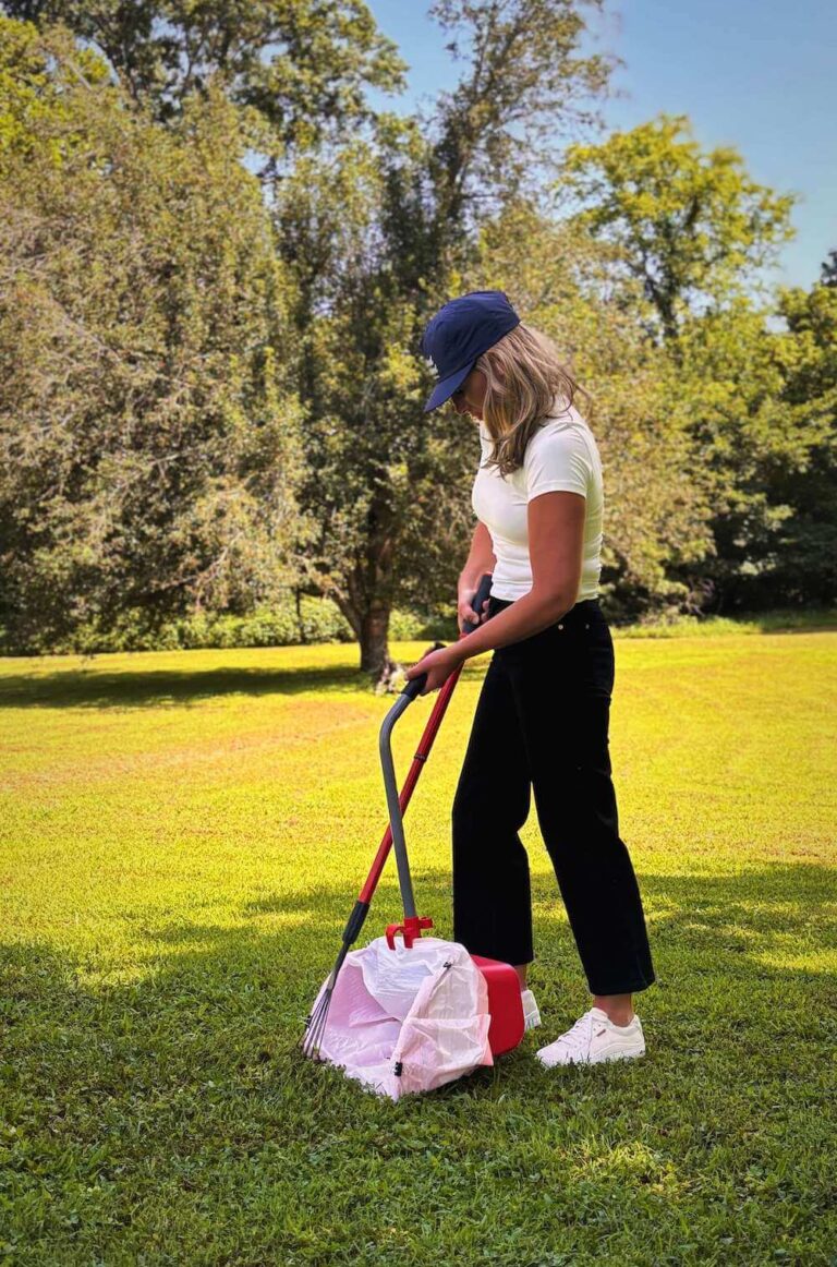 Yard Patrol technician using a scooper to clean pet waste in a grassy Nashville area