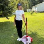 Person standing in a neatly maintained yard with cleanup tools, representing Yard Patrol lawn care services.